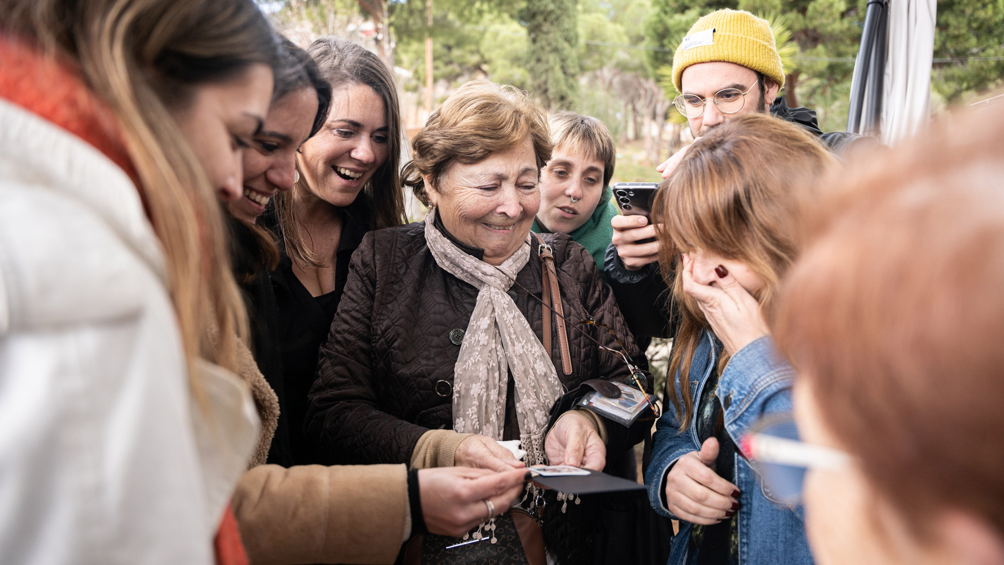 a group of people cluster around a synthetic memory with expressions of surprise